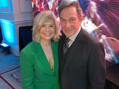 Glynis Barber is wearing a green suit and Michael Brandon is wearing a black suit.